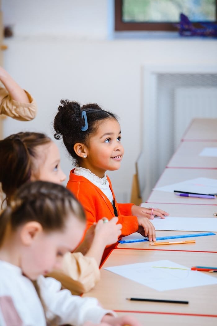 A diverse group of children in a classroom participating in activities around a table.